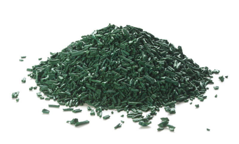 Close up of organic spirulina flakes heap over white background